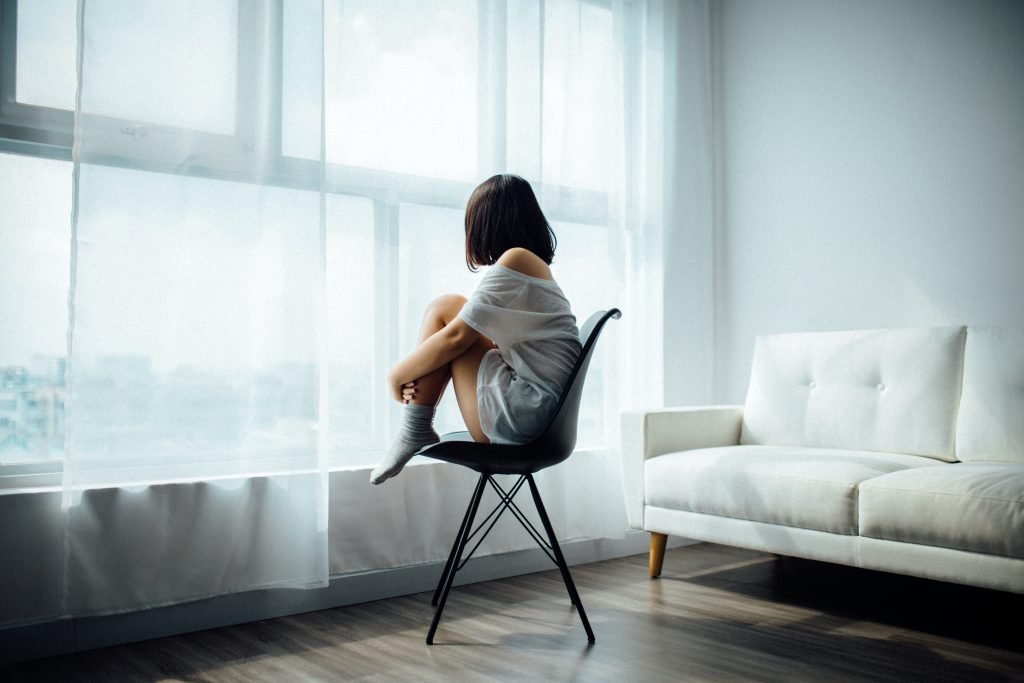 Woman sitting in a chair, looking out a window
